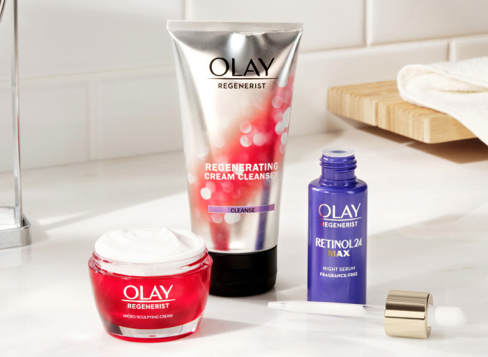 'The Everyday Essential' set on a white, minimalist bathroom counter. The set features one Olay Regenerist Regenerating  Cream Cleanser, one jar of Olay Regenerist Micro-Sculpting Cream, and one Olay fragrance-free Retinol 24 MAX Night Serum